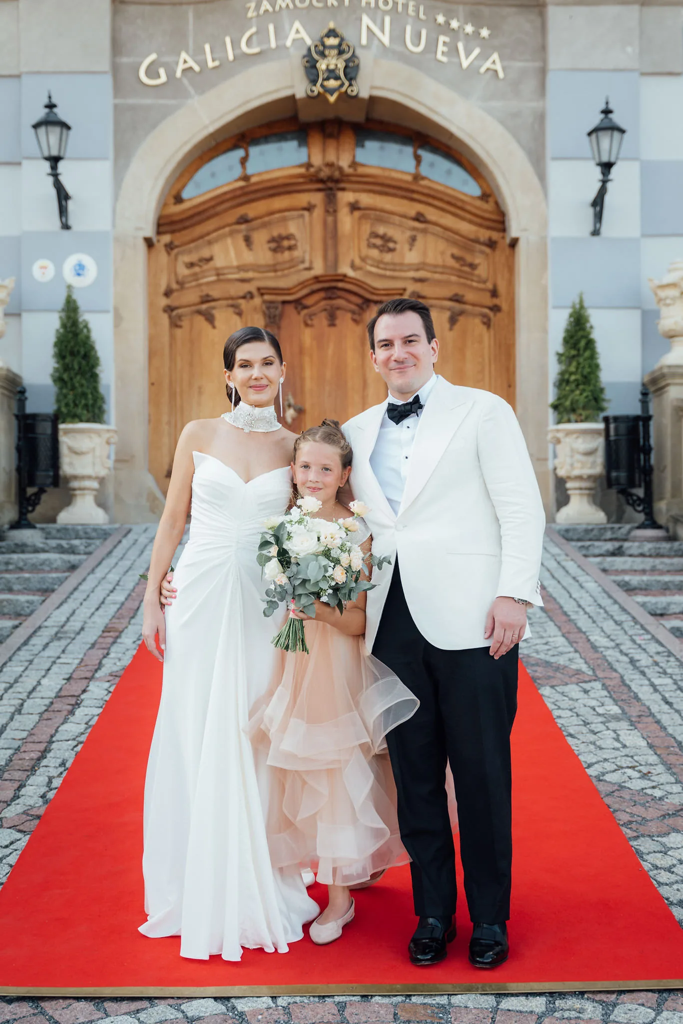 Novomanželia s malou družičkou pred bránou zámku, svadba v Galicia Nueva Halič