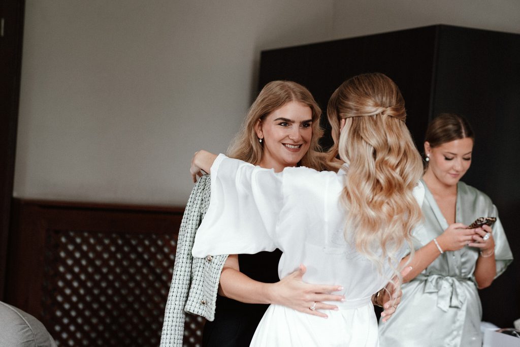 Bridesmaids helping the bride put on her dress, wedding at Chateau Appony, Oponice