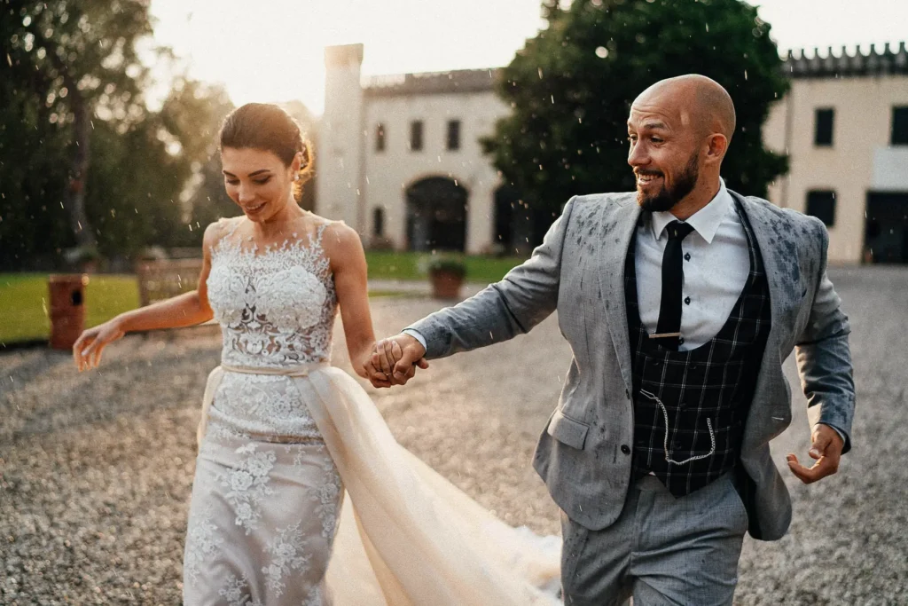 Newlyweds walking in the rain in front of a manor house
