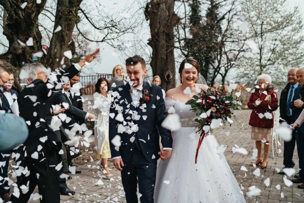 Novomanželia medzi hosťami a lupeňmi kvetov, svadobná fotografia Daniel Kaplavka