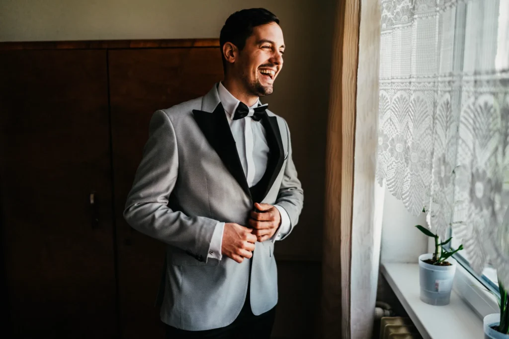 Usmiaty ženích si zapína sako, svadobná fotografia Daniel Kaplavka